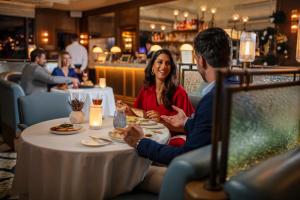 a man and woman sitting at a table in a restaurant at Four Seasons Hotel Dubai International Financial Centre in Dubai