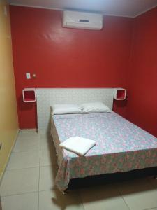 a bedroom with a bed with a red wall at Hotel 678 in Boa Vista