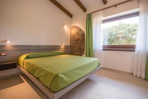 a bedroom with a green bed and a window at Villa Ginepro (Country House) in Dorgali