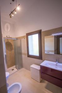 uma casa de banho com um lavatório, um WC e uma janela. em Villa Ginepro (Country House) em Dorgali