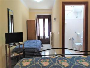 ein Schlafzimmer mit einem Bett und einem TV sowie ein Badezimmer in der Unterkunft Affittacamere Centro Storico in Raiano