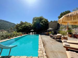 a swimming pool with chairs and a house at Fabulous Rustic Villa Set On Mountain With Unique Views in Valldemossa