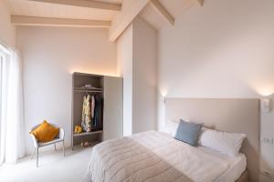 a white bedroom with a bed and a chair at Pareus Beach Resort in Caorle