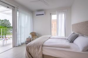 a white bedroom with a bed and a balcony at Pareus Beach Resort in Caorle