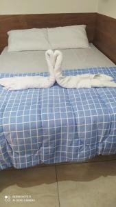 a bed with two white towels on it at Pousada Quarto família ar, frigobar,wi fi in Aparecida