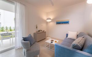 a living room with a blue couch and two chairs at Pareus Beach Resort in Caorle