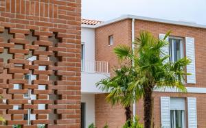 a brick building with a palm tree next to it at Pareus Beach Resort in Caorle