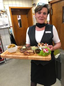 a woman holding a tray of food on a cutting board at Hessischer Hof in Bad Karlshafen