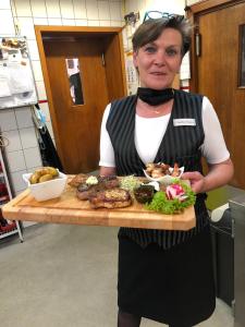 Eine Frau, die ein Tablett mit Essen auf einem Schneidebrett hält. in der Unterkunft Hessischer Hof in Bad Karlshafen