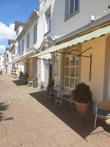 una fila de edificios con mesas y sillas en una calle en Hessischer Hof, en Bad Karlshafen