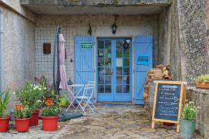 a restaurant with a blue door and a sign and flowers at Maison Rives - Village du Livre de Montolieu in Montolieu