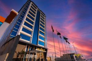 a building with flags in front of it with a sunset at The Gate Hotel and Apartments in Dammam