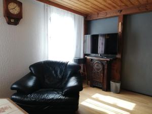 a black leather chair in a living room with a clock at San Marco Vip in Fluelen
