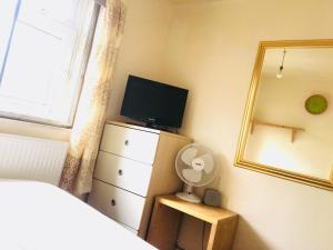 a bedroom with a television and a dresser with a mirror at COSY ROOM 2 LONDOn in London