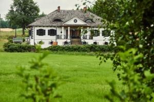 Biały dom z ogródkiem z zieloną trawą w obiekcie Impresja - pokoje gościnne na nadbużańskich łąkach w mieście Borsuki
