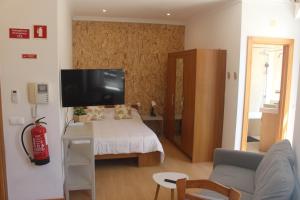 a room with a bed and a tv and a couch at Studios by Blue Door in Portimão
