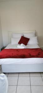 a white bed with a red blanket and white pillows at Lytton Cresent B&B in Pinetown