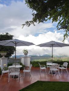 a patio with tables and chairs and umbrellas at Daleside Manor, Boutique Hotel, Kasauli in Kasauli