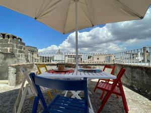 una mesa con sillas y una sombrilla en el balcón en Le Cementine house Vacanze Salento, en Galatone