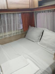 a bed with white sheets and pillows in a room at каравана Марбея in Chernomorets