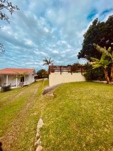 una casa con una valla y un campo de hierba en Pousada Essência do Rosa, en Praia do Rosa