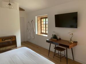 a bedroom with a desk and a television on the wall at LE CARGE D’ARLAY in Charnay-lès-Mâcon
