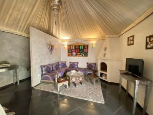 un salon avec un canapé violet et une télévision dans l'établissement Eden Lodges & SPA, à Marrakech