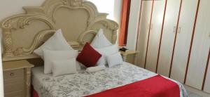 a bedroom with a large bed with red and white pillows at Lytton Cresent B&B in Pinetown