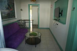 ein Wohnzimmer mit einem lila Sofa und einem Tisch in der Unterkunft Passion Fruit Apartment in Aschkelon
