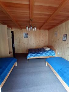 two beds in a room with wooden walls at Noclegi Leśniczówka w Lanckoronie in Lanckorona