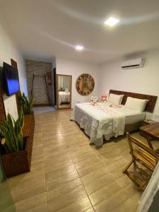 1 dormitorio con 1 cama y reloj en la pared en CHOUPANA SUÍTES en Japaratinga