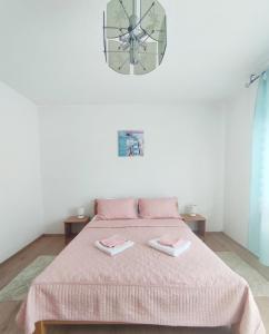 a bedroom with a bed with a pink blanket and a clock at Guesthouse D&D in Ličko Petrovo Selo