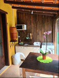 a kitchen with a table and a stove and a sink at Casinha Astral - Praia da Ferrugem in Garopaba