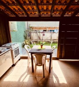 a table and chairs in a kitchen with a table and a stove at Casinha Astral - Praia da Ferrugem in Garopaba