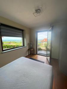 um quarto com uma grande cama branca e uma grande janela em Casa Arge em La Morra