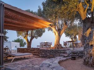 a patio with trees and tables and a stone wall at Tainaron Blue Retreat in Vathia