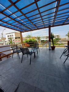 een patio met stoelen en tafels en een blauwe baldakijn bij El Capricho Paracas in Paracas