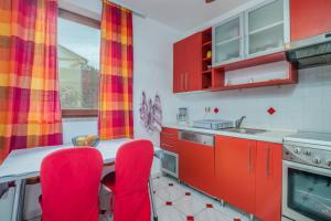 una cocina con armarios rojos y sillas rojas en Apartment Dora Klimno, en Klimno
