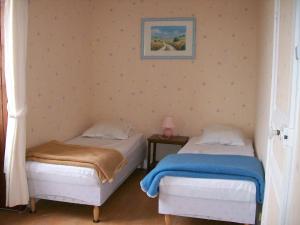 Gîte "L'helpe" dans grande maison quercynoise entre Sarlat Rocamadour في غوردون أون كيرسي: سريرين في غرفة نوم مع صورة على الحائط