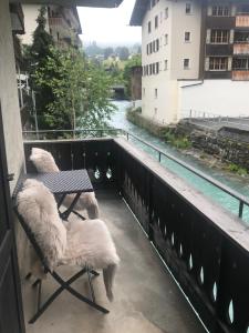 a balcony with two chairs and a table and a river at TOP LOCATION - Klosters center - 130m distance to ski lift Parsenn Gotschnabahn and railway station Klosters Platz - direct connection to Davos in Klosters