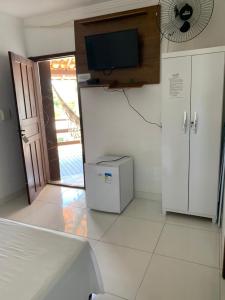 a white room with a television and a refrigerator at Pousada Escarpas in Capitólio