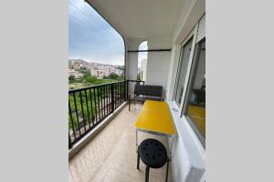 balcón con taburete amarillo y banco en Sunny apartment by the river, en Sandanski