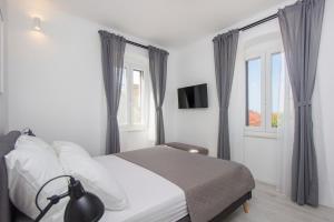 a bedroom with a bed and two windows at Apartment Ena ,city center in Šibenik