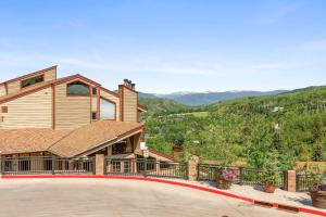 a large house with a balcony with mountains in the background at Snowmass 2br Getaway Pool, Hot Tub & Ski Access - D2 in Snowmass Village
