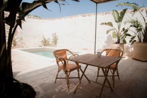 a wooden table and two chairs on a patio with a pool at Masseria Calderisi in Savelletri di Fasano