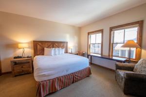 a bedroom with a bed and a chair and windows at Beautifully Renovated Two Bedroom Condo with a Balcony in Mountaineer Square condo in Crested Butte