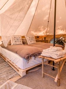 Bett in einem Zelt mit Leinwand und Tisch in der Unterkunft BohoFyn in Nyborg