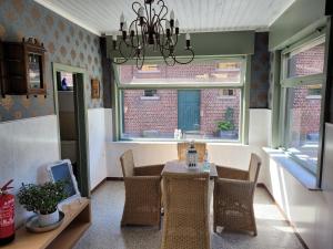 ein Esszimmer mit einem Tisch, Stühlen und einem Kronleuchter in der Unterkunft vakantiewoning hoeve 'd oude scheure in Kortemark