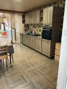 a kitchen with wooden cabinets and a wooden floor at Guest House Barbi in Batumi