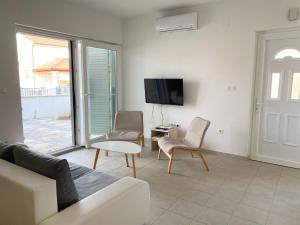 a living room with a tv and a couch and chairs at Luminus Apartments in Srima